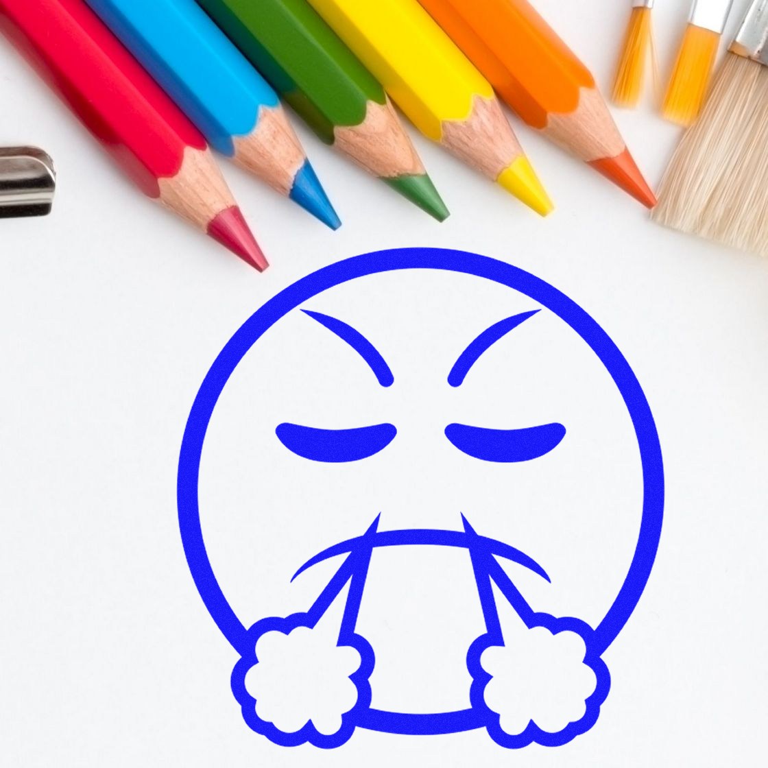 Self-Inking Steamy Sam Emoticon Stamp with a blue angry face design, surrounded by colorful pencils and brushes on a white background.