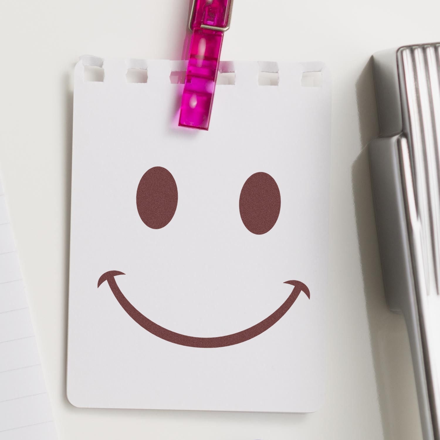 Self-Inking Cheeky Smirk Emoji Stamp on notepad, featuring a playful smirk design. Perfect for adding fun to notes and documents.