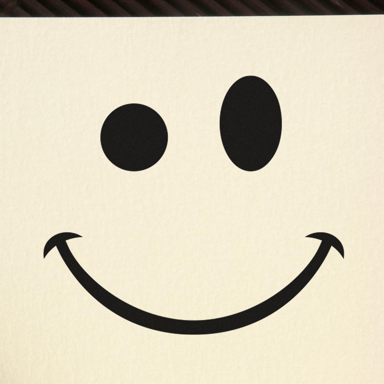 Wood Handle Mischievous Grin Emoji Rubber Stamp on paper, showcasing a playful smiley face design. Perfect for adding a fun touch to crafts and stationery.