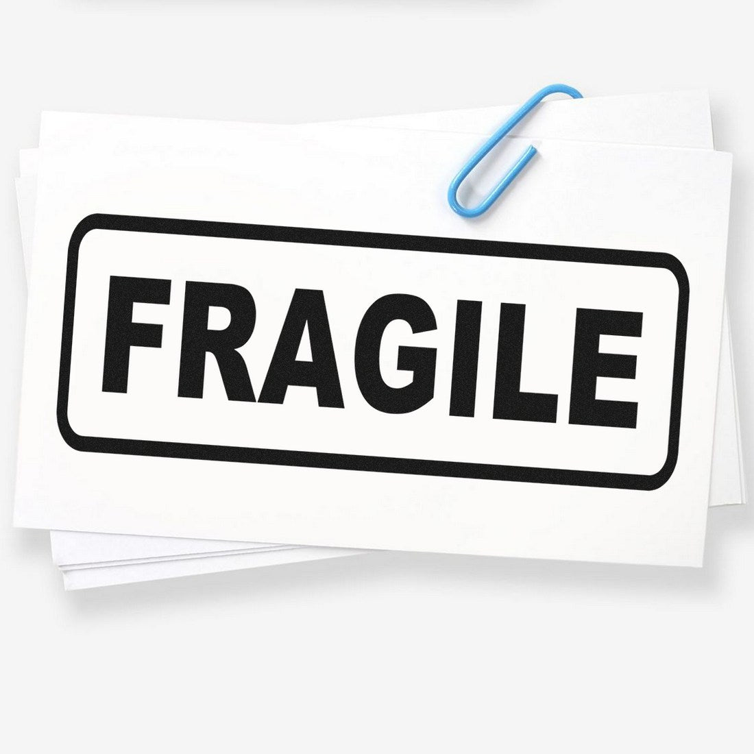 Image of a Slim Pre-Inked Fragile Stamp with bold black FRAGILE text on a white background, ideal for marking packages. Compact design with a blue paperclip for scale.