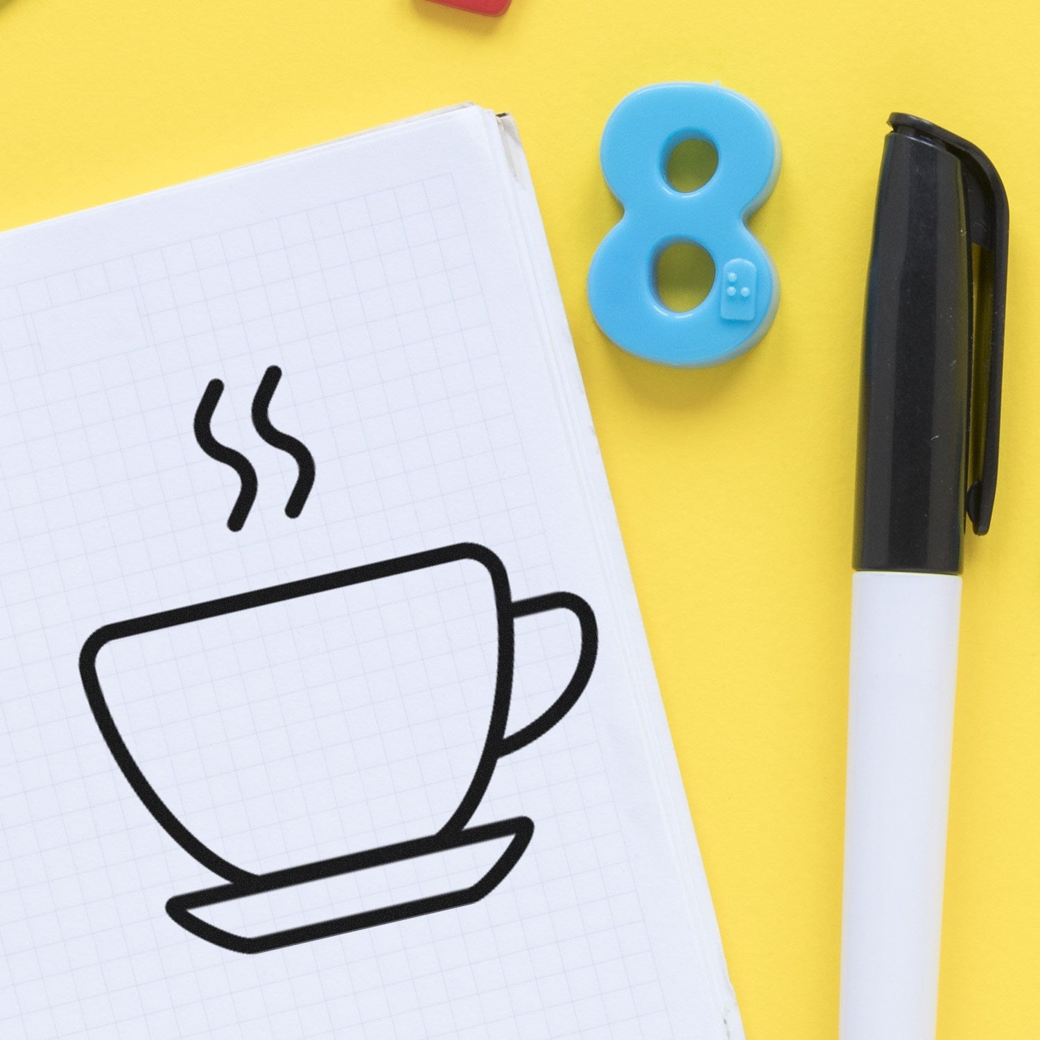 Wood Handle Steaming Coffee Cup Loyalty Rubber Stamp on a notepad with a steaming cup design, alongside a black pen and a blue number eight magnet on a yellow background.