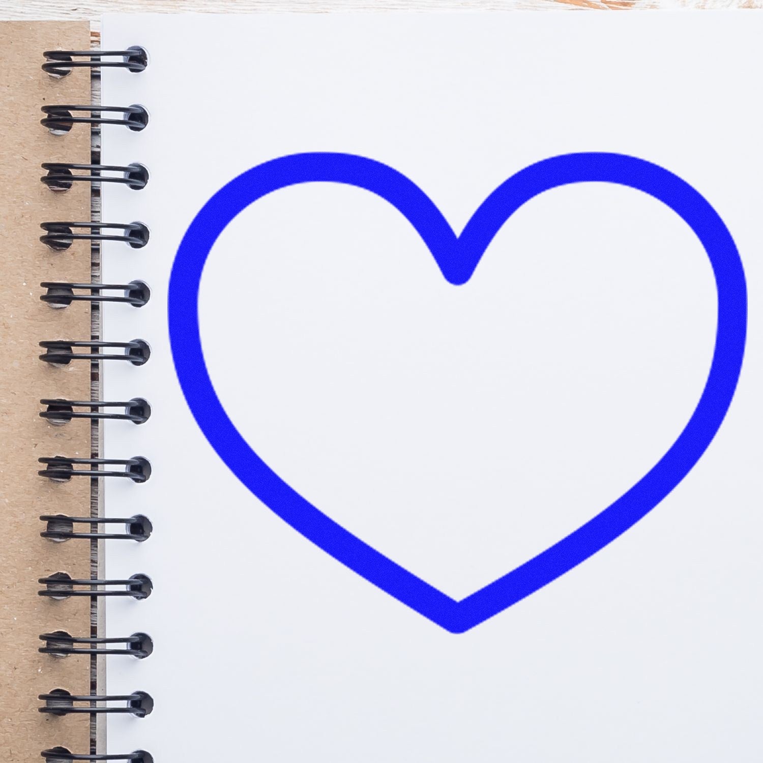 Wood Handle Heartfelt Loyalty Purchase Rubber Stamp with a blue heart design, shown on a spiral-bound notebook. Ideal for crafting and personalizing stationery.