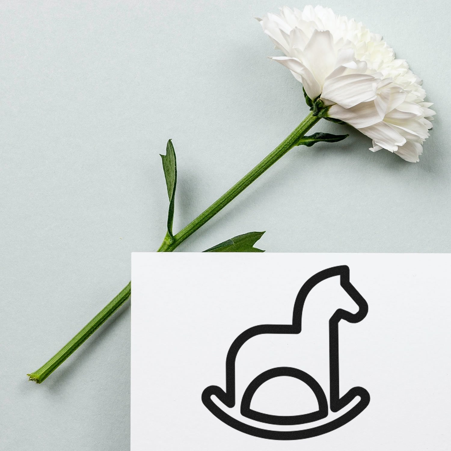 Wood Handle Rocking Horse Delight Loyalty Scheme Rubber Stamp with a simple horse design, placed beside a white flower on a light gray background.