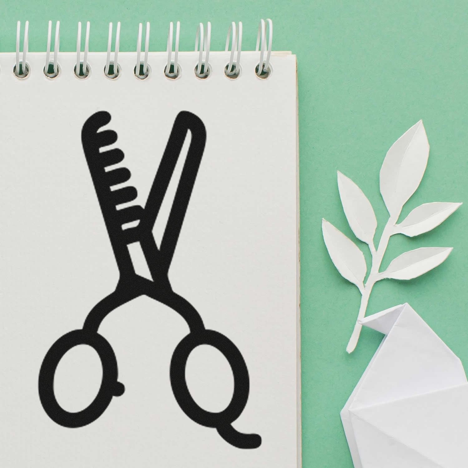 Self-Inking Stylin for Discounts Stamp featuring a black scissors and comb design on a spiral notebook, set against a green background with paper leaves. Perfect for salon promotions.