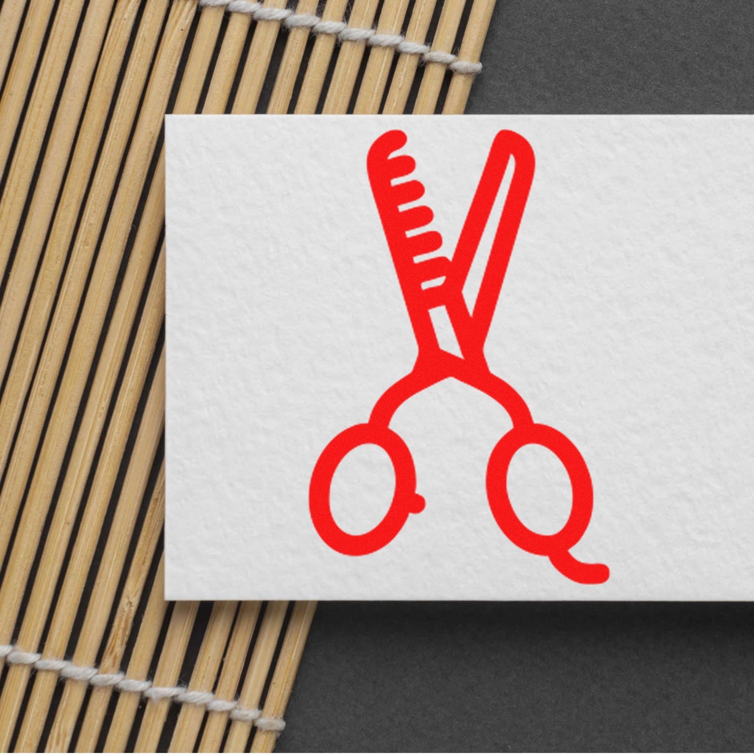 Wood Handle Stylin for Discounts Rubber Stamp featuring a red comb and scissors design on a white card, placed on a bamboo mat background.