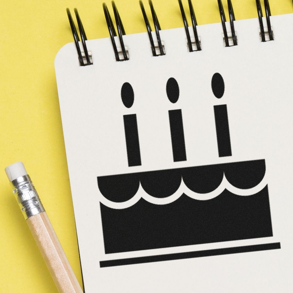 Wood Handle Cake Delight Incentive Rubber Stamp featuring a cake with candles design, displayed on a notepad with a pencil, against a yellow background.