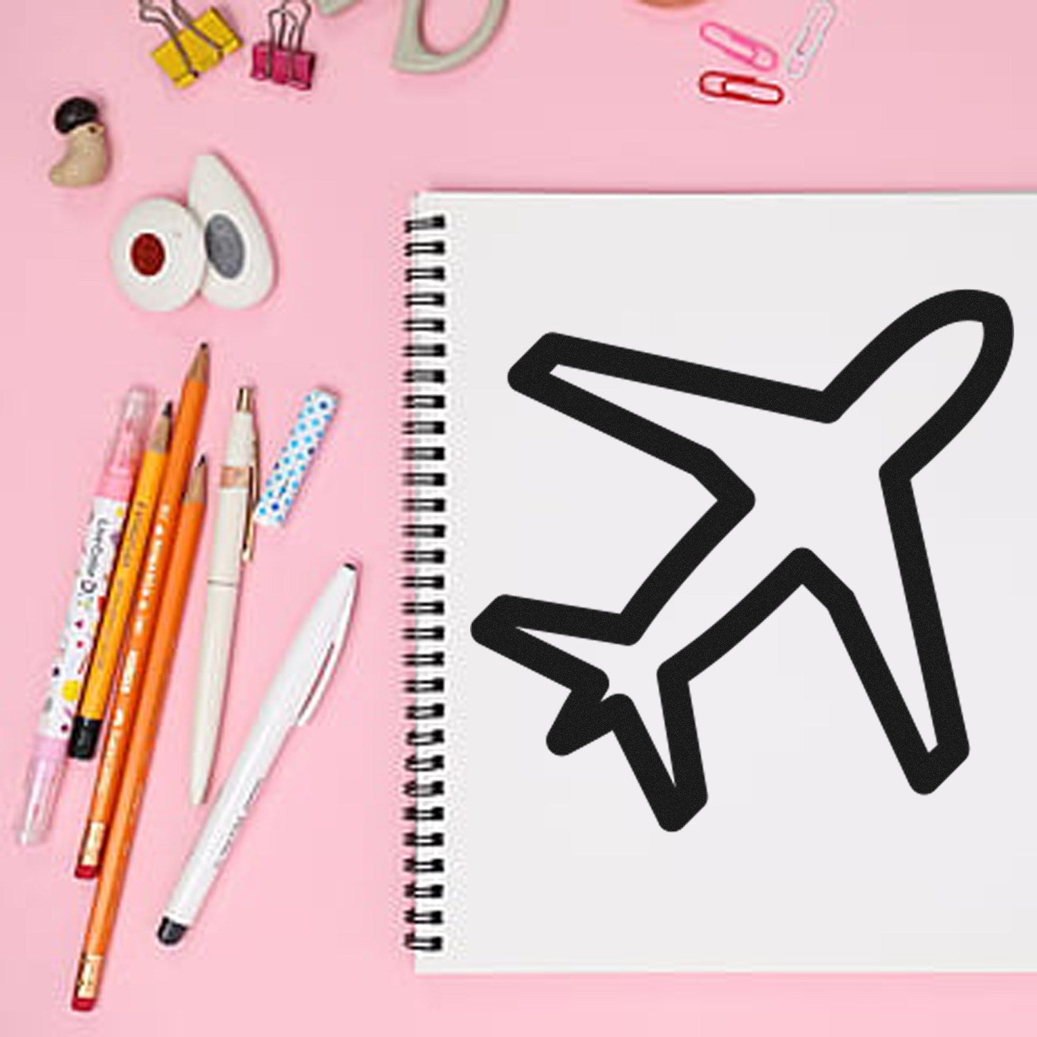 Wood Handle Jetsetter-Based Rewards Rubber Stamp with airplane design on a pink desk, surrounded by pens and paper clips.