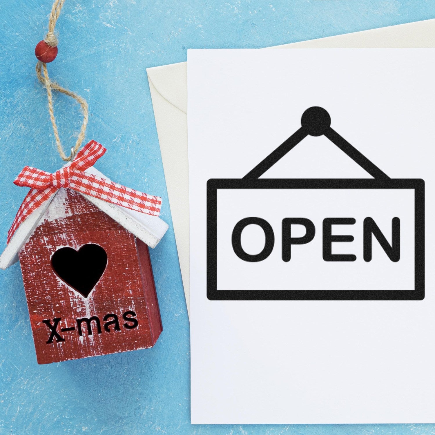 Wood Handle Open Sign Loyalty Rubber Stamp on blue background, featuring a wooden house with a heart and 'X-mas' text, alongside an 'OPEN' sign graphic.