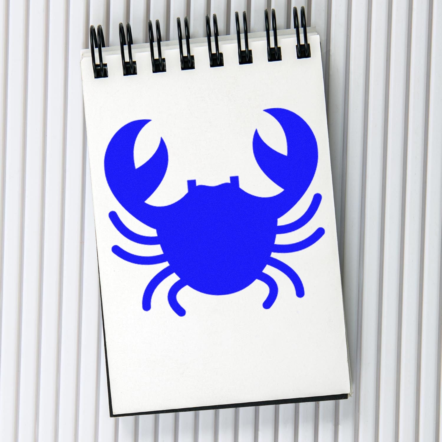 Self-Inking Crabby Rewards Stamp with a vibrant blue crab design on a spiral notepad, perfect for teachers and parents to motivate and reward children.