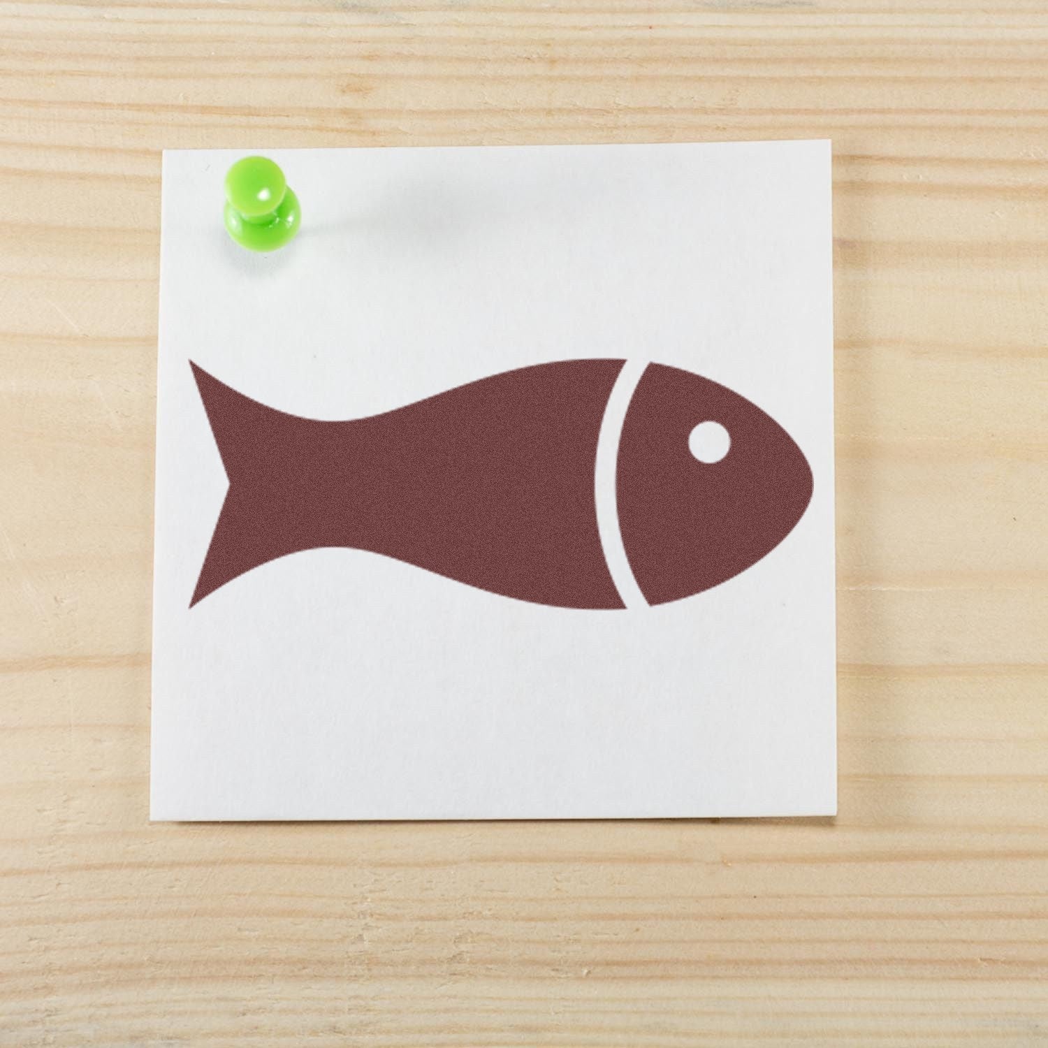 Wood Handle Fin-Tastic Loyalty Incentive Rubber Stamp featuring a fish design on paper, pinned with a green pushpin on a wooden surface.