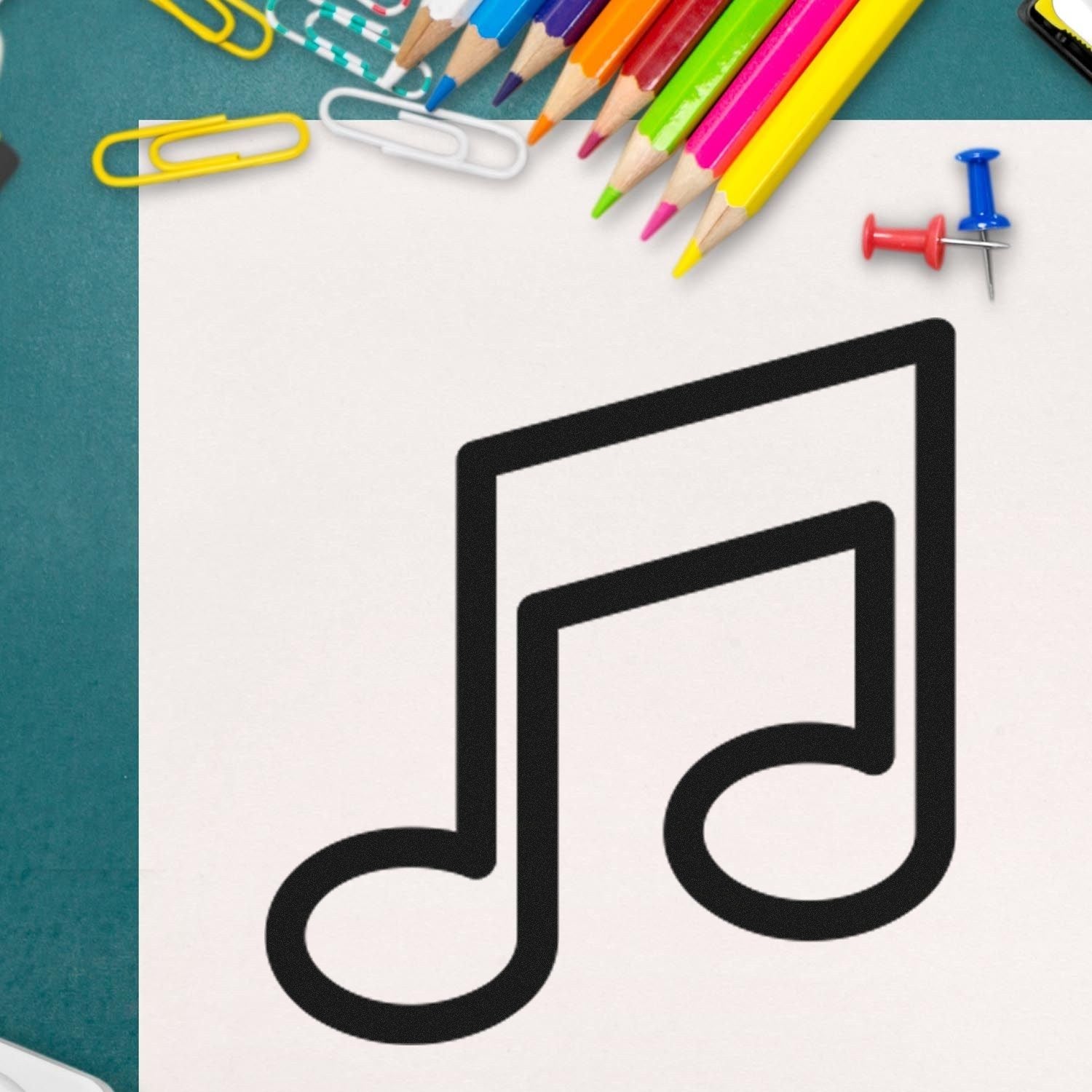 Wood Handle Melody Mark Card Reward Rubber Stamp featuring a musical note design, surrounded by colorful pencils and paperclips on a desk. Perfect for teachers and creative projects.