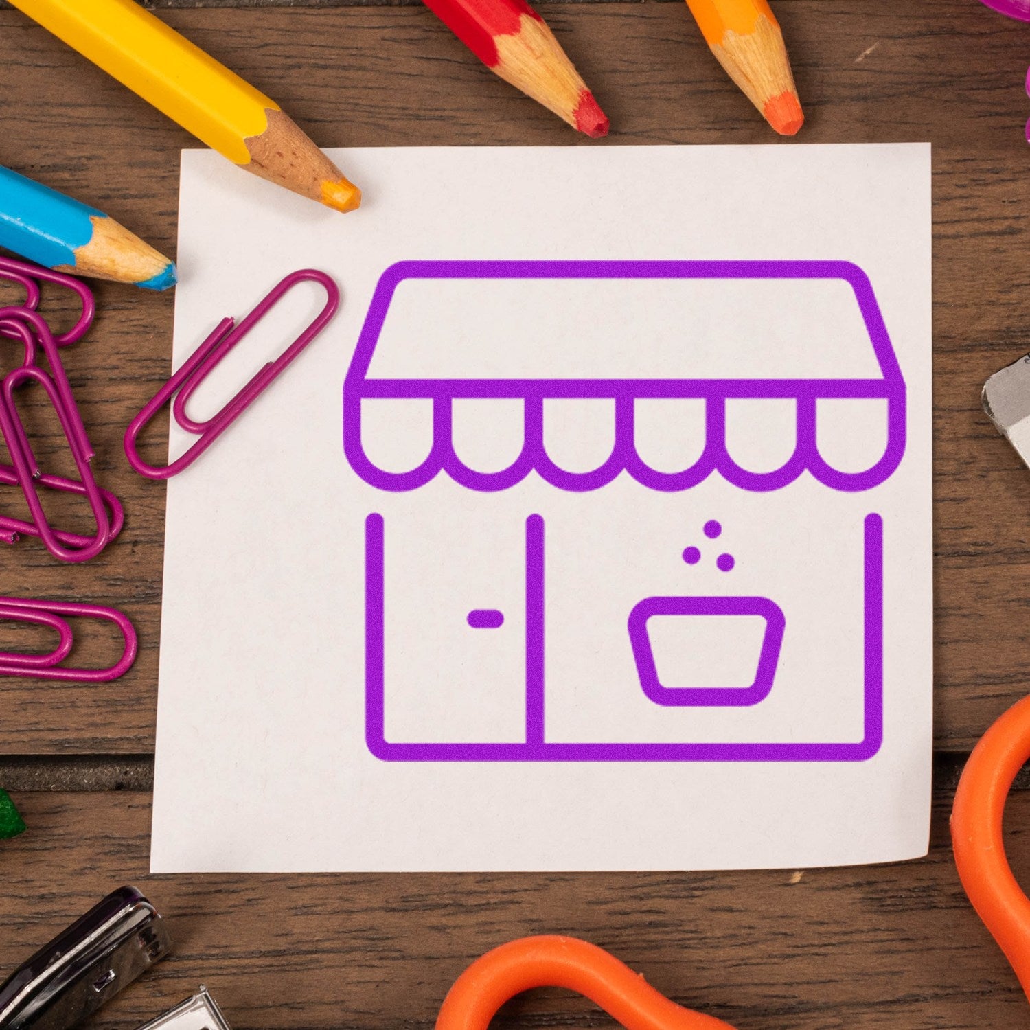 Image of a Self-Inking Coffee Shop Loyalty Stamp with a purple coffee shop icon on white paper, surrounded by colorful stationery on a wooden table.