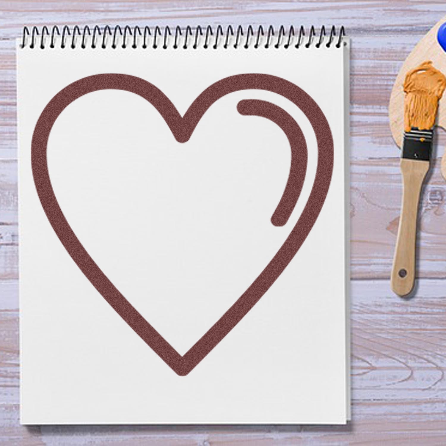 Self-Inking Heartfelt Loyalty Stamp imprinting a large brown heart on white paper, with a wooden table and paintbrush in the background.