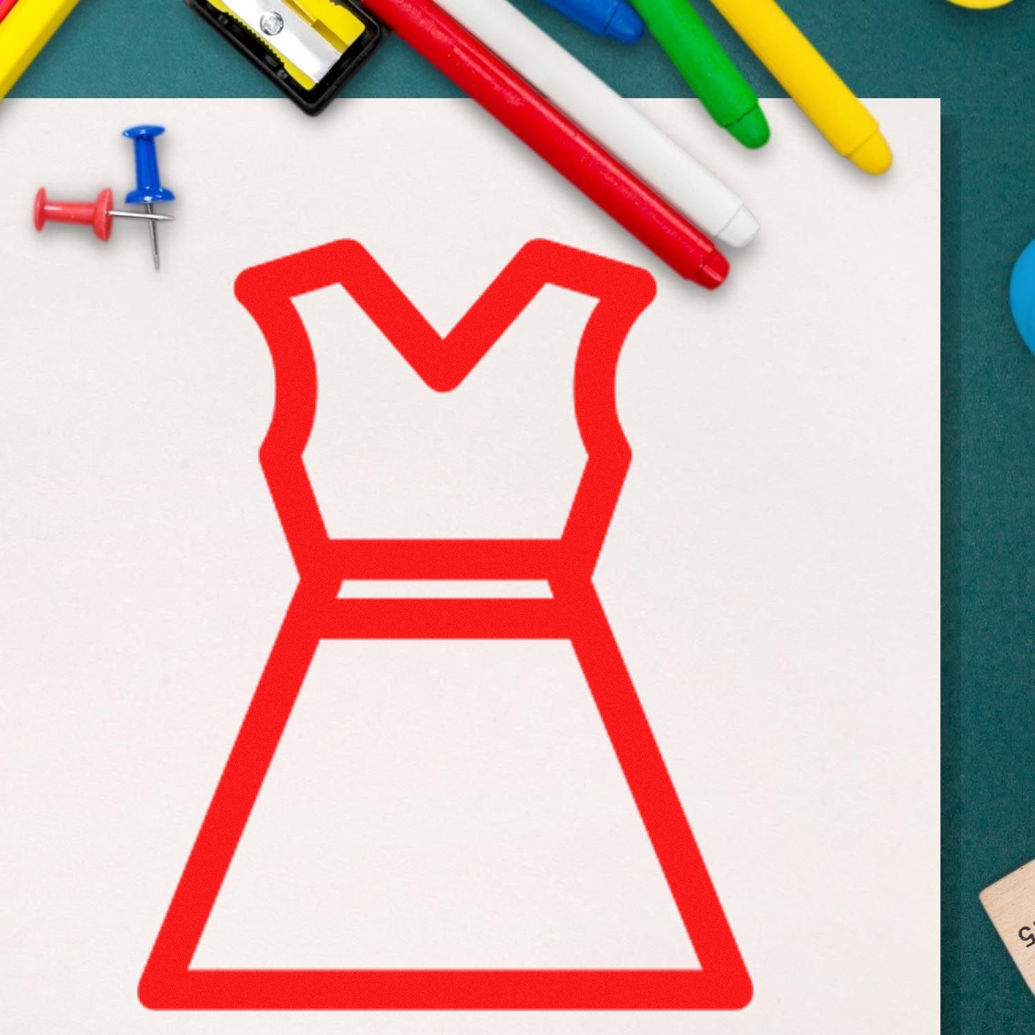 Self-Inking Clothing Punch Card Stamp in use, featuring a red dress outline on white paper, surrounded by colorful markers and push pins. Perfect for fabric marking and crafting.