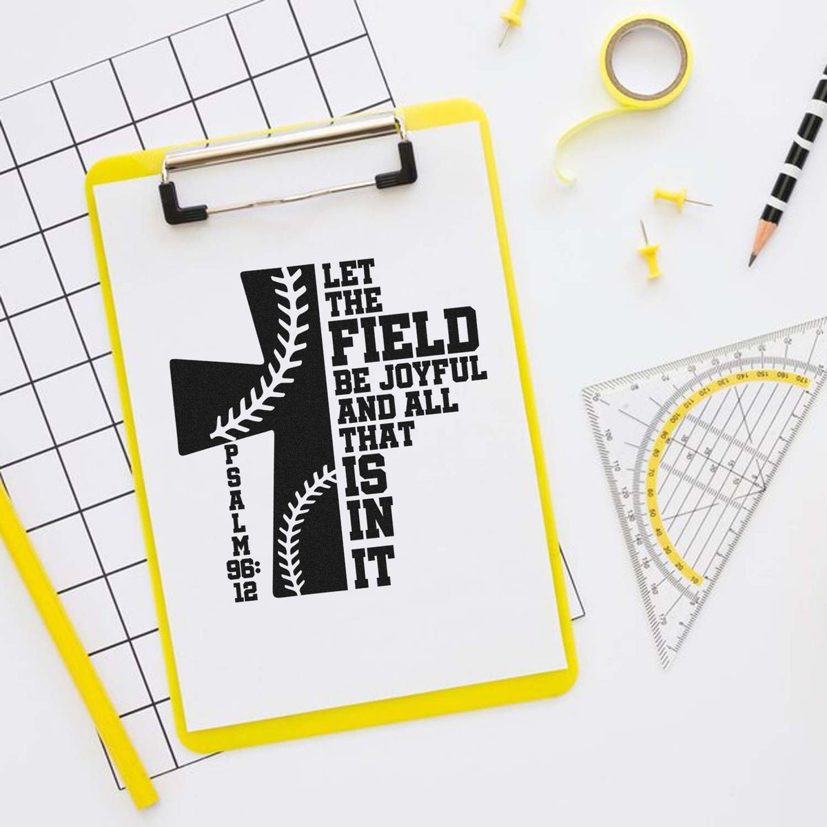 Yellow clipboard stamp/seal with black baseball Psalm 96:12 design, beside drafting tools and pencil.