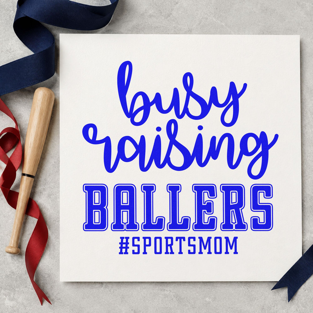 Busy Raising Ballers craft stamp in blue ink on cardstock, an easy option for canvas game bags.