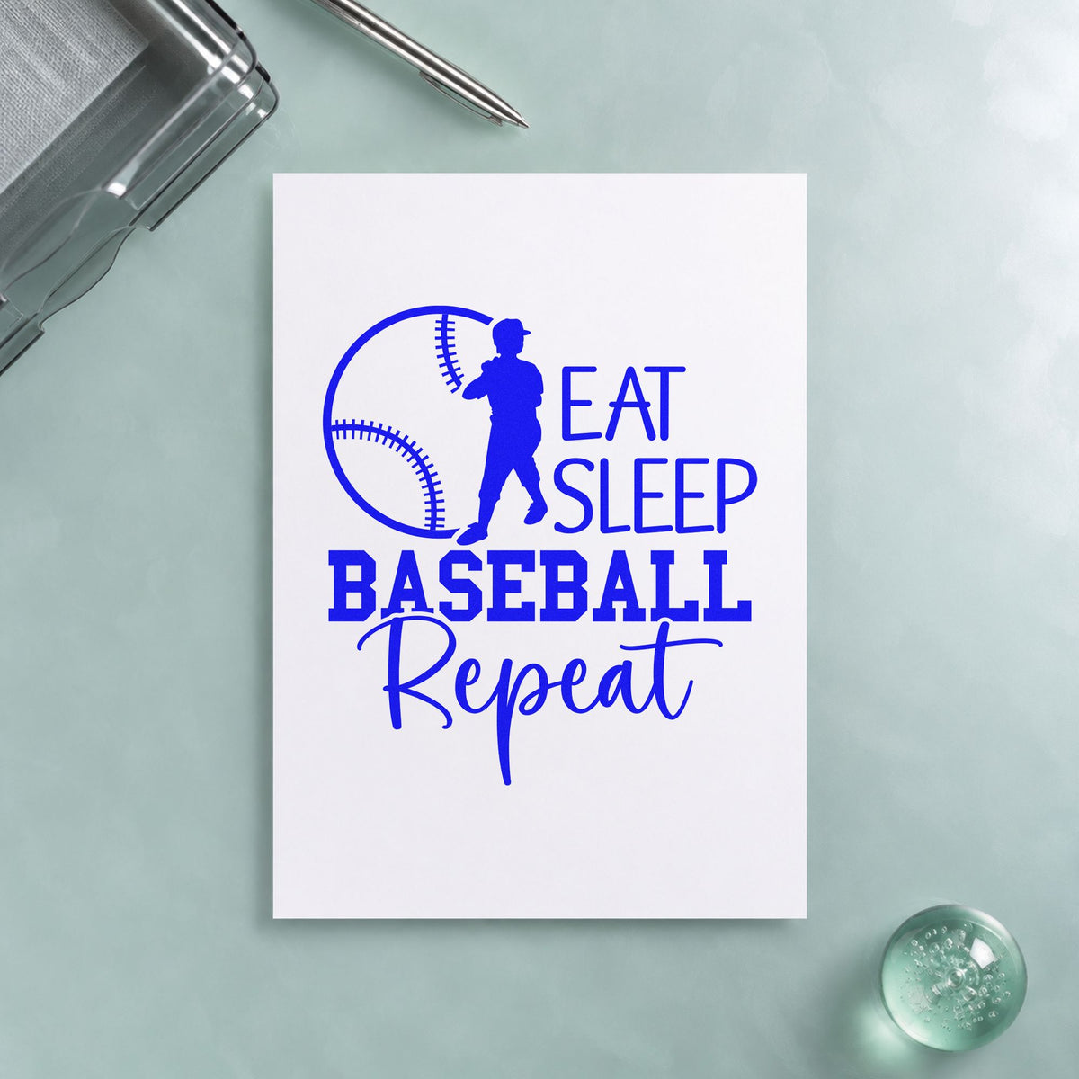 Eat Sleep Baseball Repeat craft stamp imprinted in blue ink on paper, a design suited to lunchbox notes.