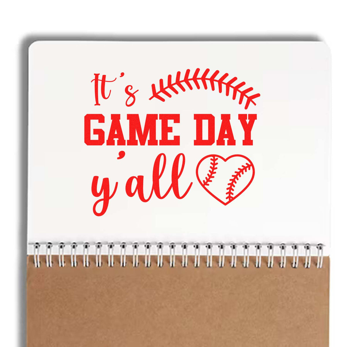 Red baseball-themed stamp/seal reading Its GAME DAY yall, with heart, on white and tan notebook background