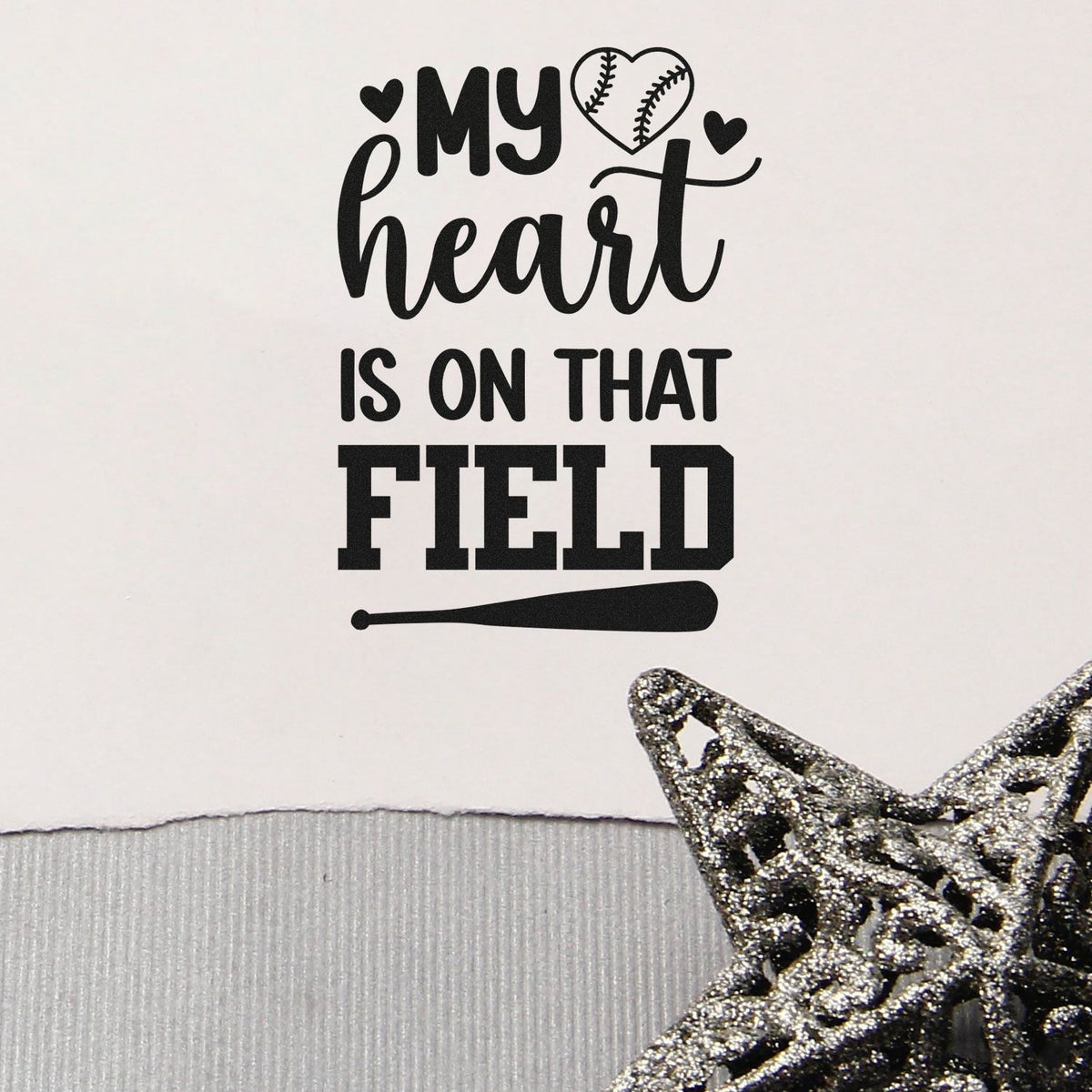 Black baseball-themed stamp reading my heart is on that field with heart, bat, and silver glitter star on white.
