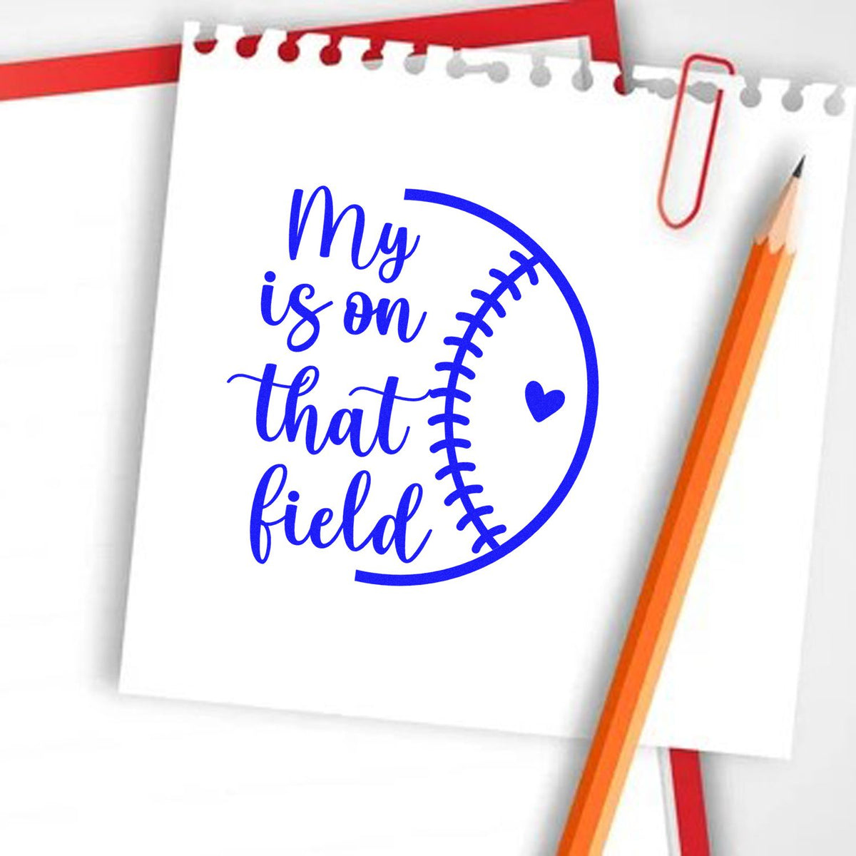 Blue baseball stamp and seal design reading My is on that field on white paper, with red paperclip and orange pencil.