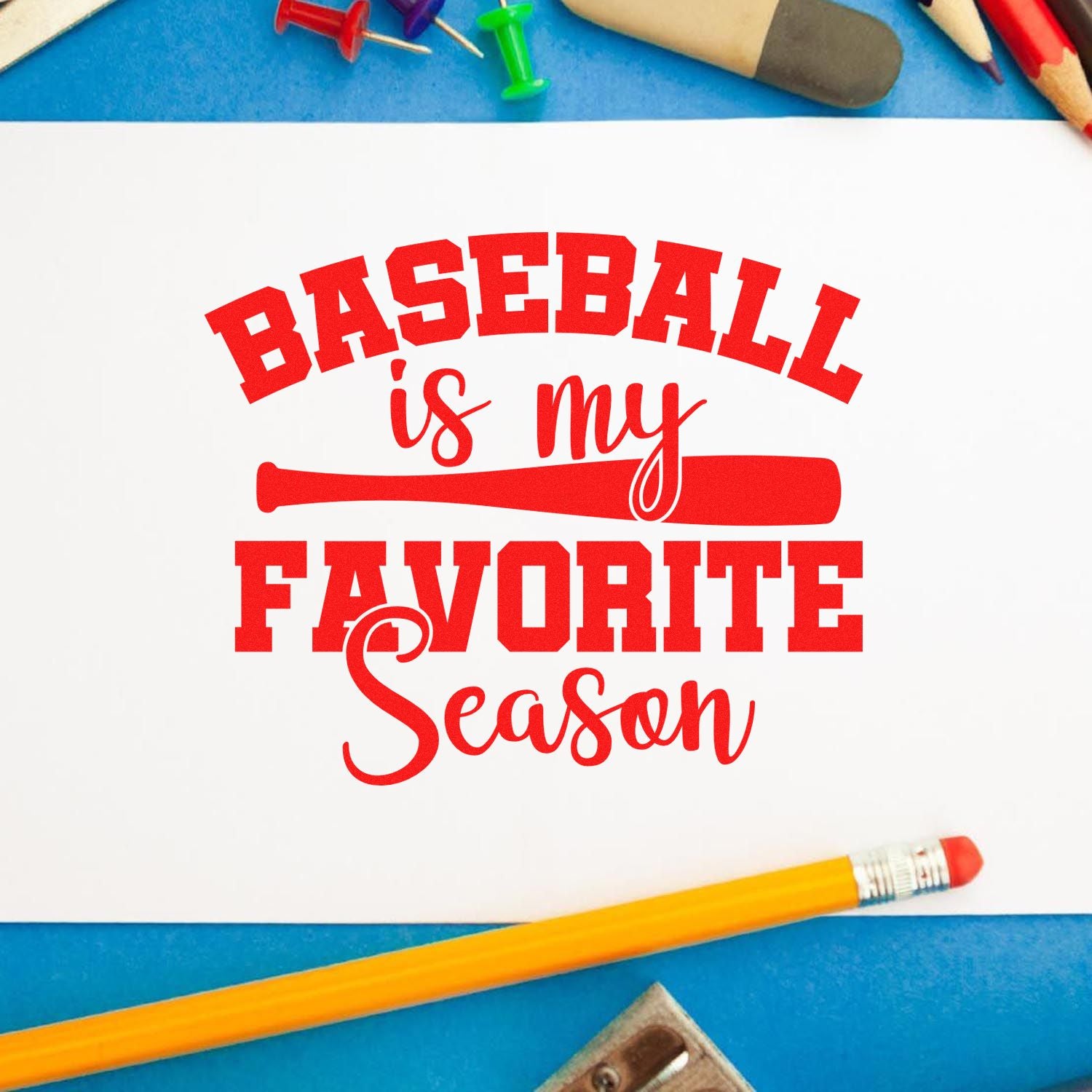 Red baseball stamp and seal design reading Baseball is my favorite season with bat graphic on white, on blue desk with pencils.