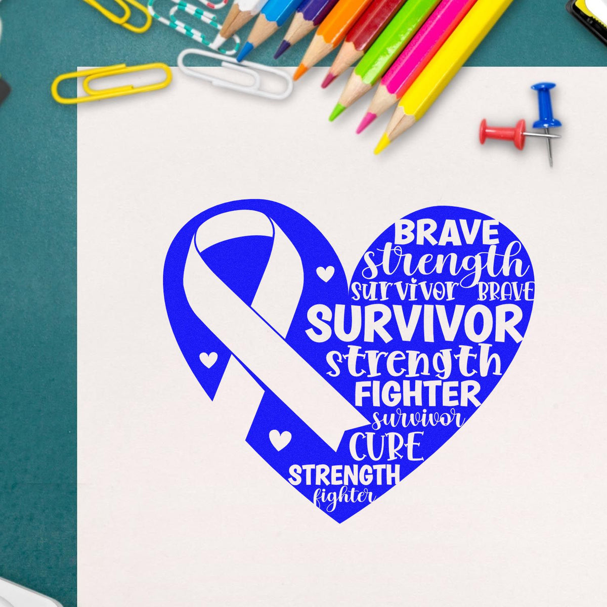 Blue breast cancer survivor heart ribbon stamp and seal design with white text, colored pencils, paperclips, and push pins.
