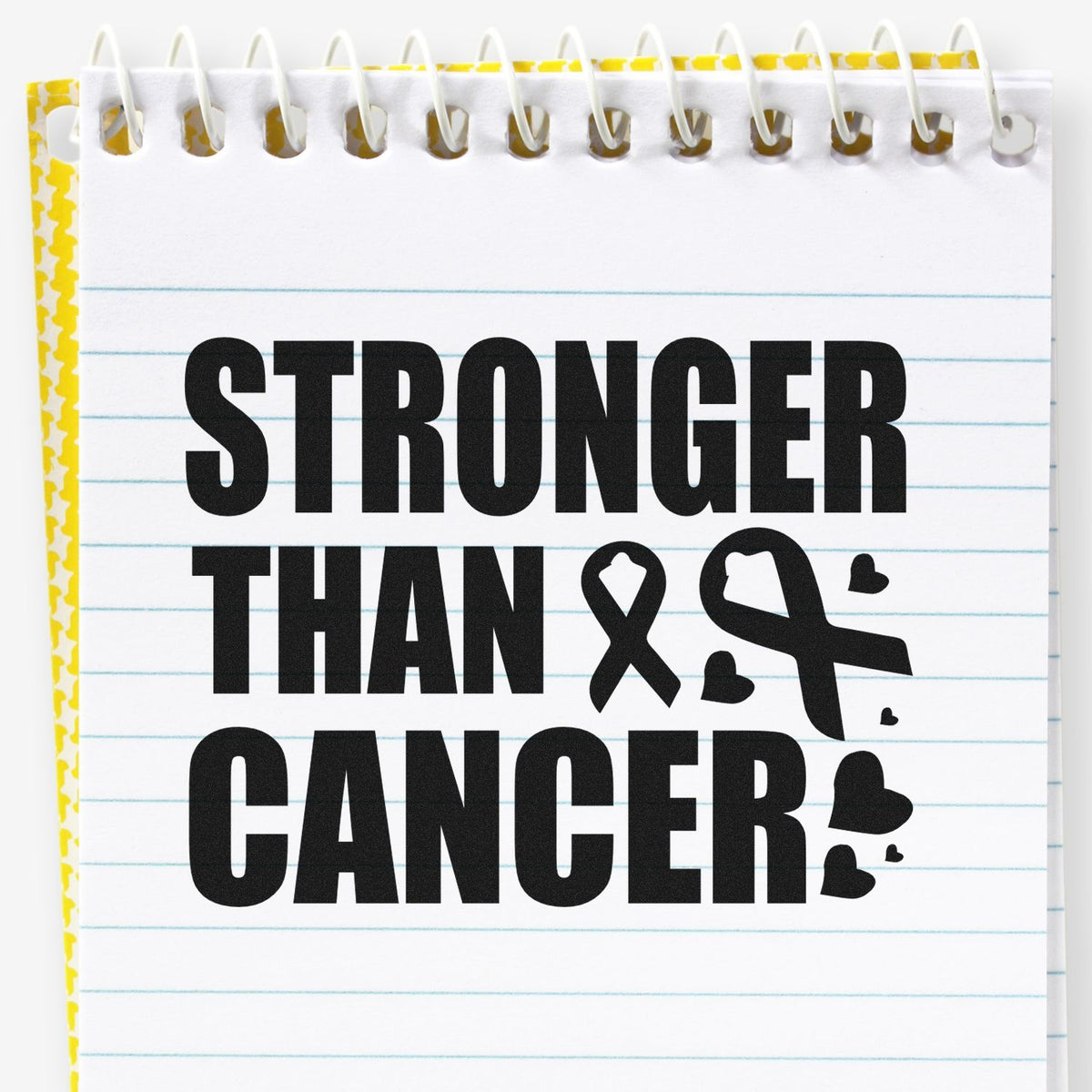 Black STRONGER THAN CANCER stamp on white spiral notepad with yellow border, blue lines, ribbon, and hearts.