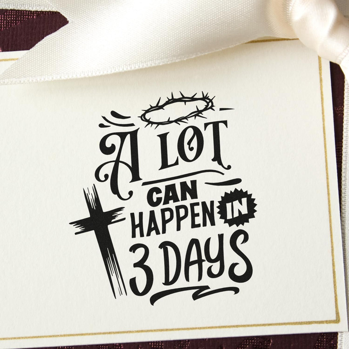 Black religious stamp seal on ivory card with gold trim, reading A lot can happen in 3 days, with cross and crown of thorns.