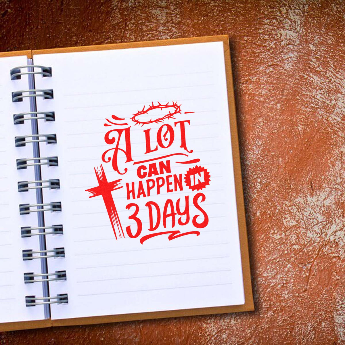 Red Christian stamp and seal reading A lot can happen in 3 days, with crown of thorns on a white spiral notebook.