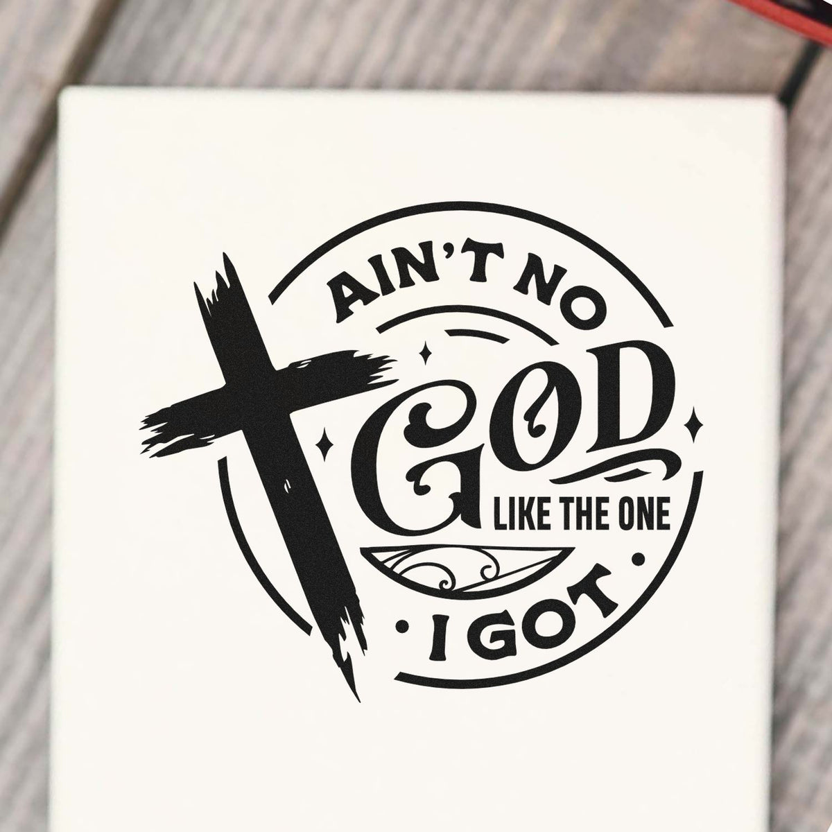 Black faith-based rubber stamp seal with brushstroke cross and circular text: Aint no God like the one I got on white.