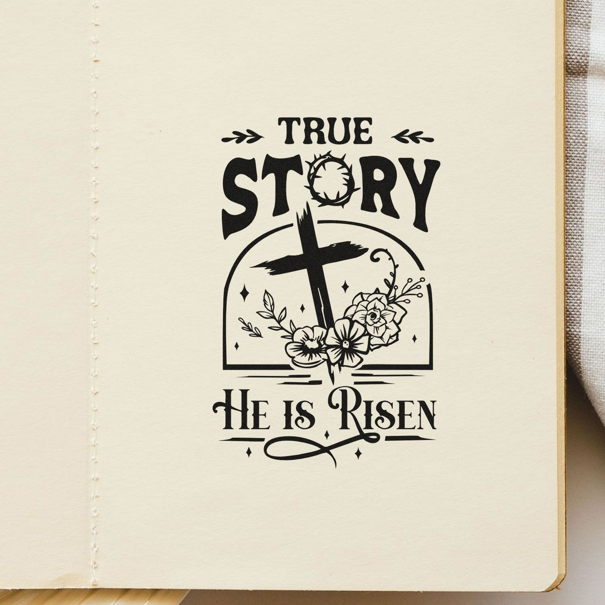 Black rubber stamp design reading True Story, He Is Risen with cross, flowers, and vintage lettering on cream paper.