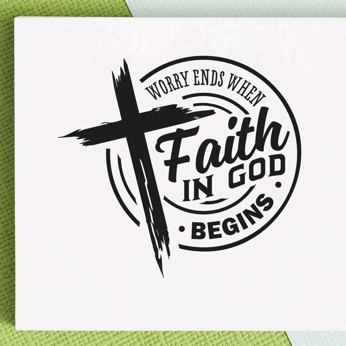 Black faith stamp and seal design with cross and circular text, Worry ends when faith in God begins, on a white card.