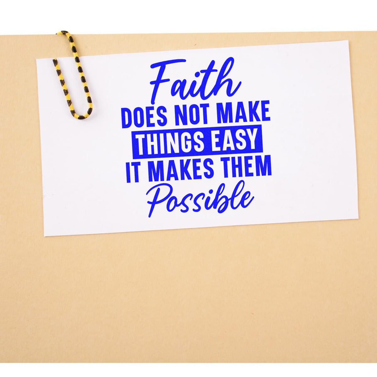 Blue faith quote stamp/seal on white card with yellow-black paperclip: Faith does not make things easy; it makes them possible.