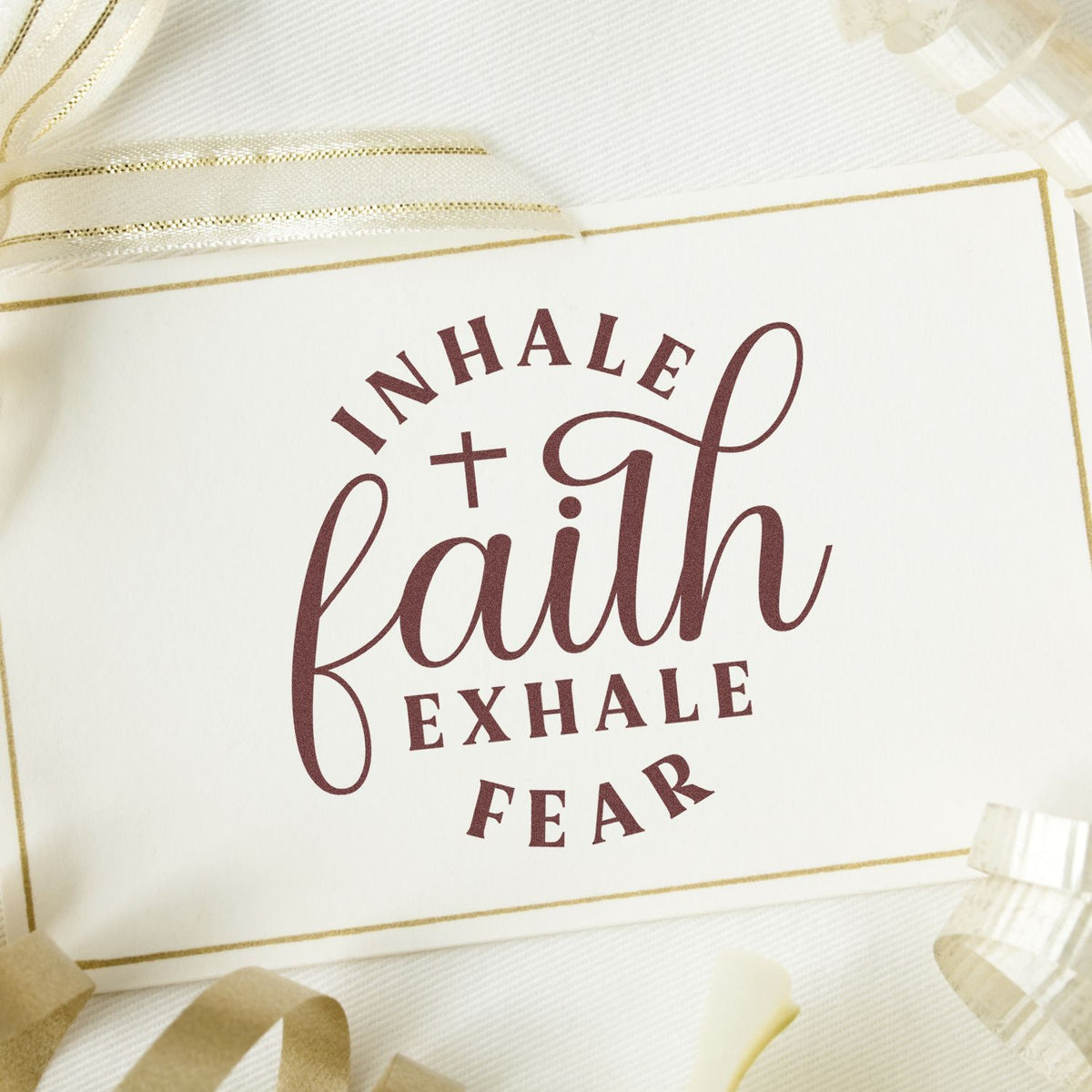 Maroon faith stamp and seal on white card with gold border and sheer ribbon, reading Inhale faith, exhale fear.