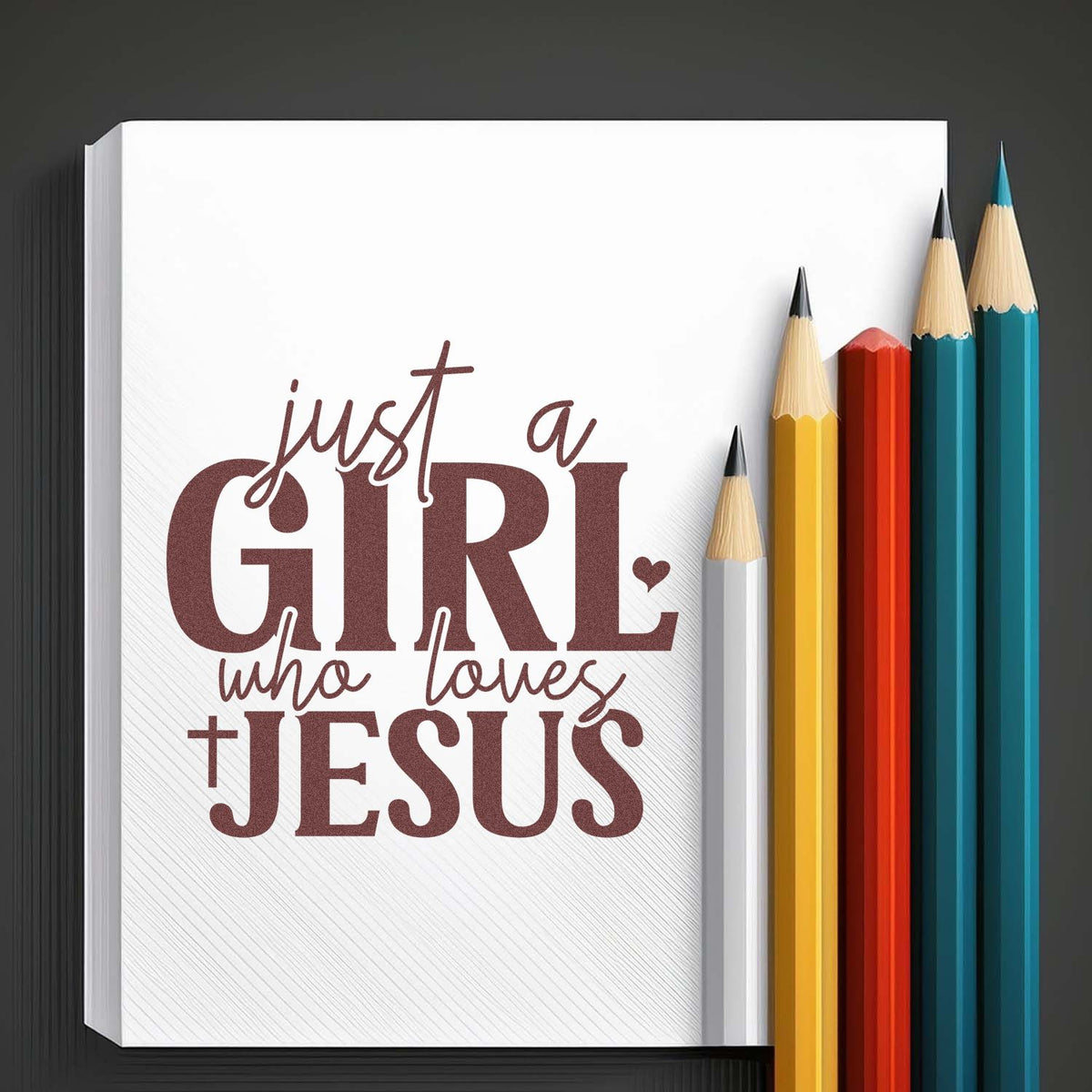 White stamp and seal design reading Just a girl who loves Jesus, with maroon lettering and colorful pencils on dark background.