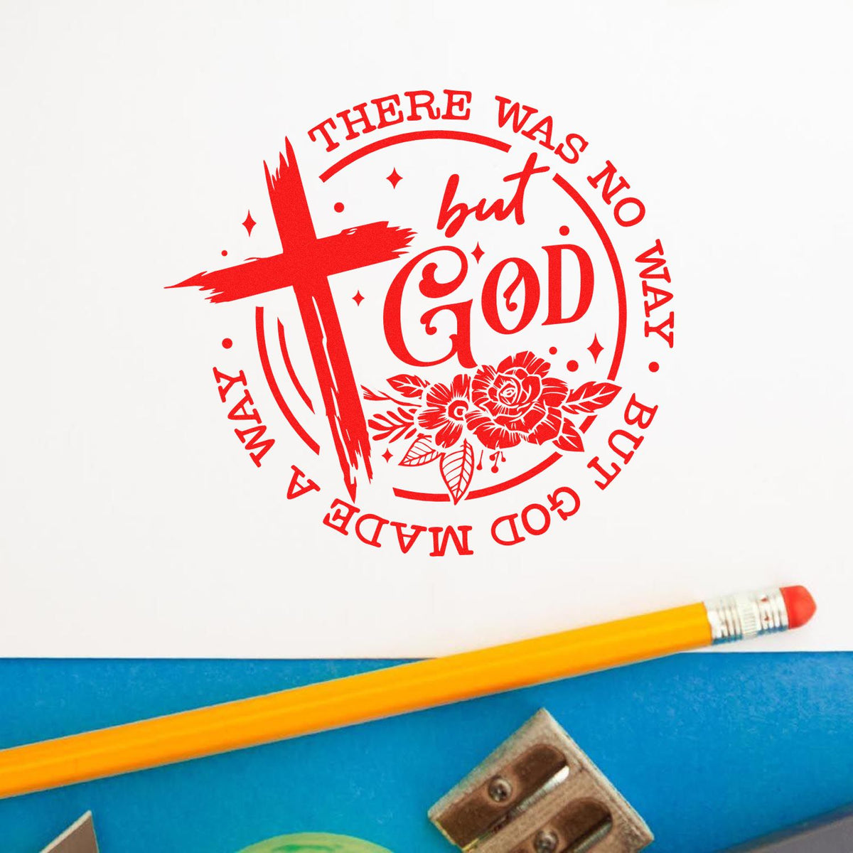 Red circular stamp seal with cross, floral accents, and There was no way but God on white paper beside a yellow pencil.