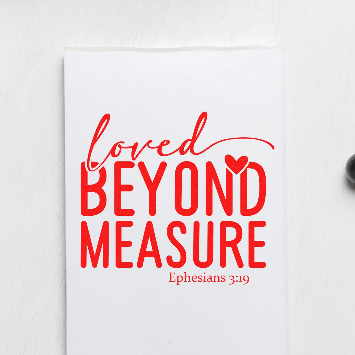 Red stamp-style seal on white paper with Loved Beyond Measure and Ephesians 3:19 in bold script.