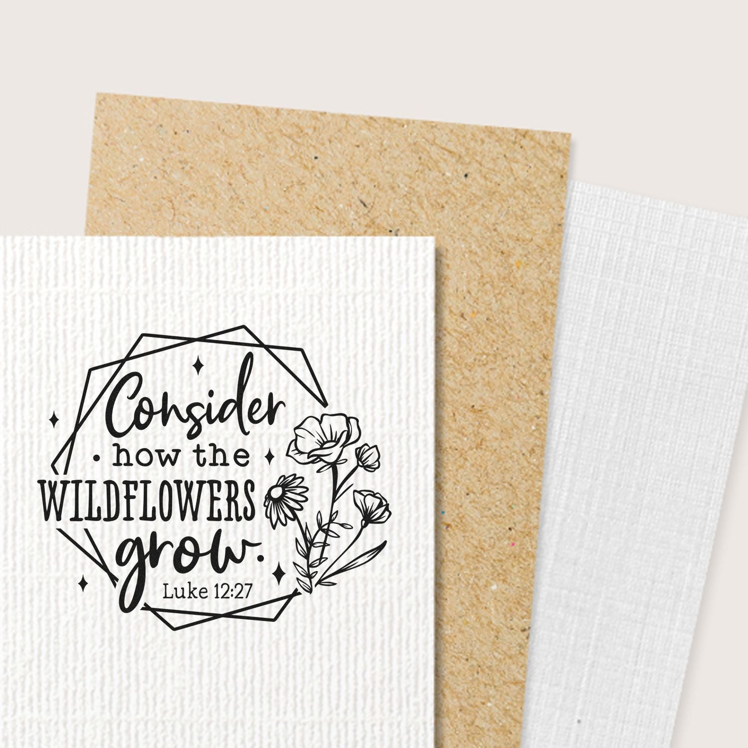 Black floral stamp and seal design with quote Consider how the wildflowers grow on white textured card, tan and white backdrop.