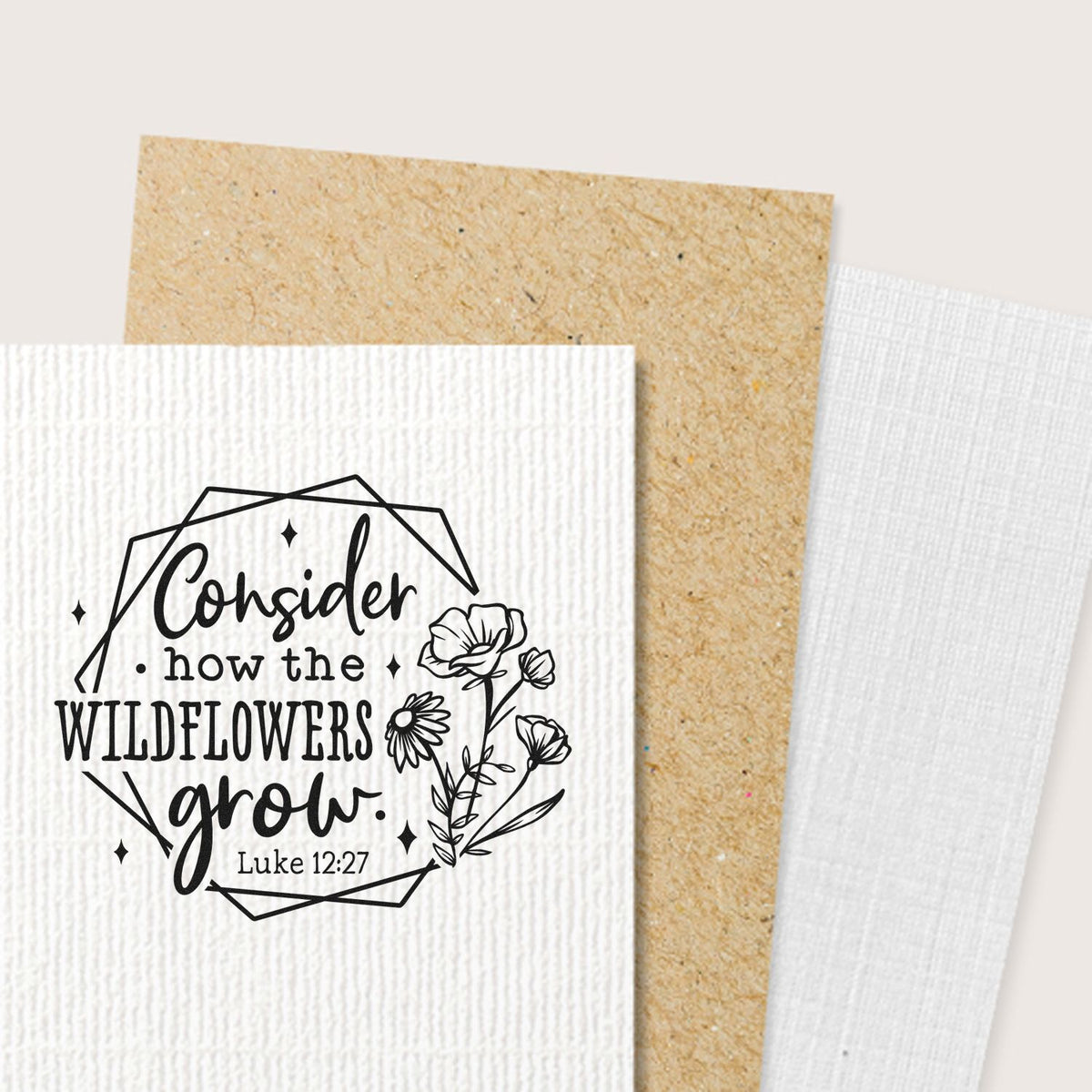 Black floral rubber stamp on textured white and kraft seal cards, reading Consider how the wildflowers grow with Luke 12:27.