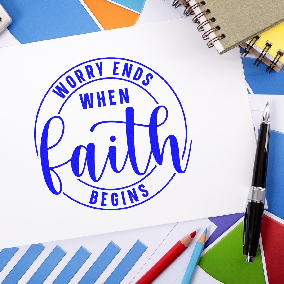 Blue circular stamp seal reading Worry ends when faith begins on white paper, surrounded by colorful stationery.