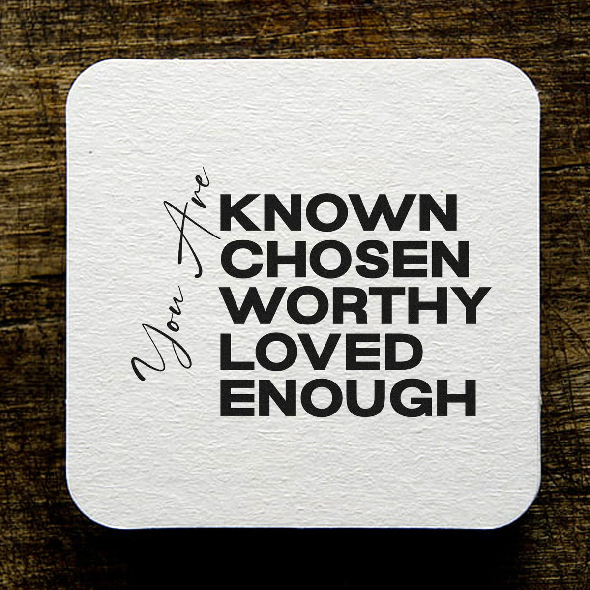 White textured stamp seal with bold black text, Known Chosen Worthy Loved Enough, and script name Jae on wood background.
