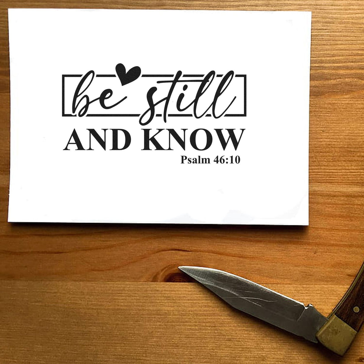 Be Still And Know Premium Wooden Stamp - Vintage Pro imprint stamped in blue ink. A rectangular outline and heart accent "Be still and know," with Psalm 46:10 below.