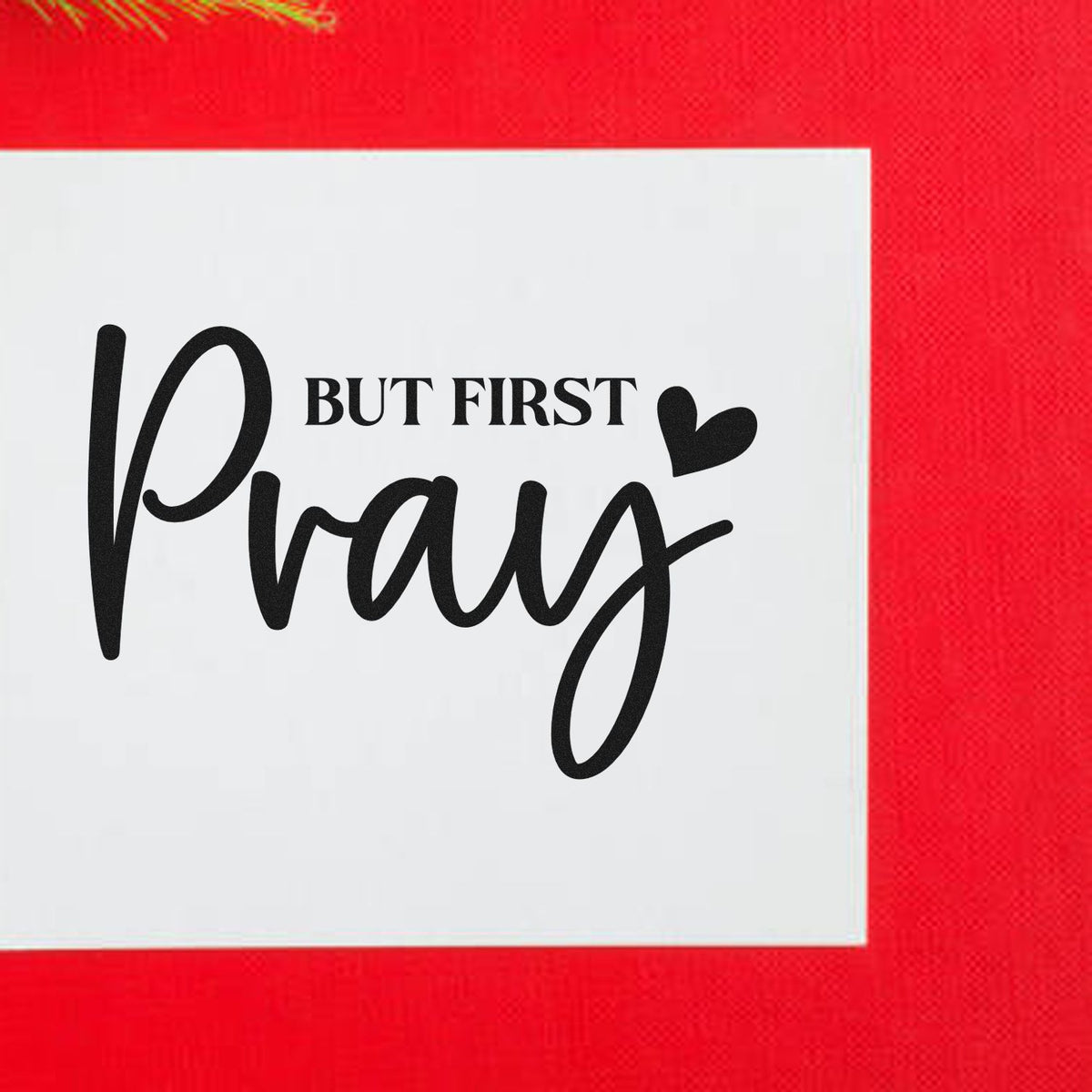 Red stamp seal design with white square, black But First Pray script, and heart accent.