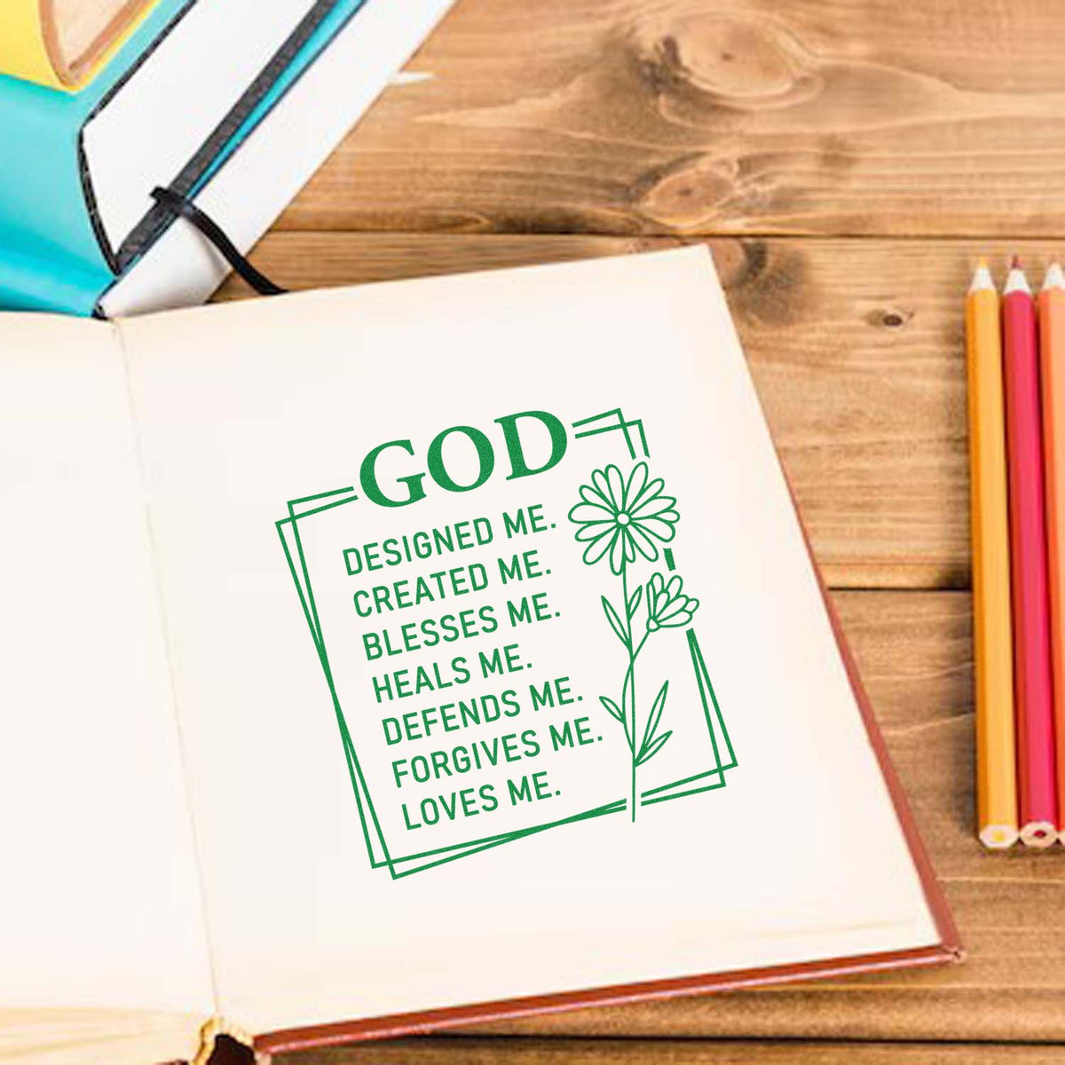 Green custom stamp seal design with floral border and faith text in an open notebook on a wood desk.