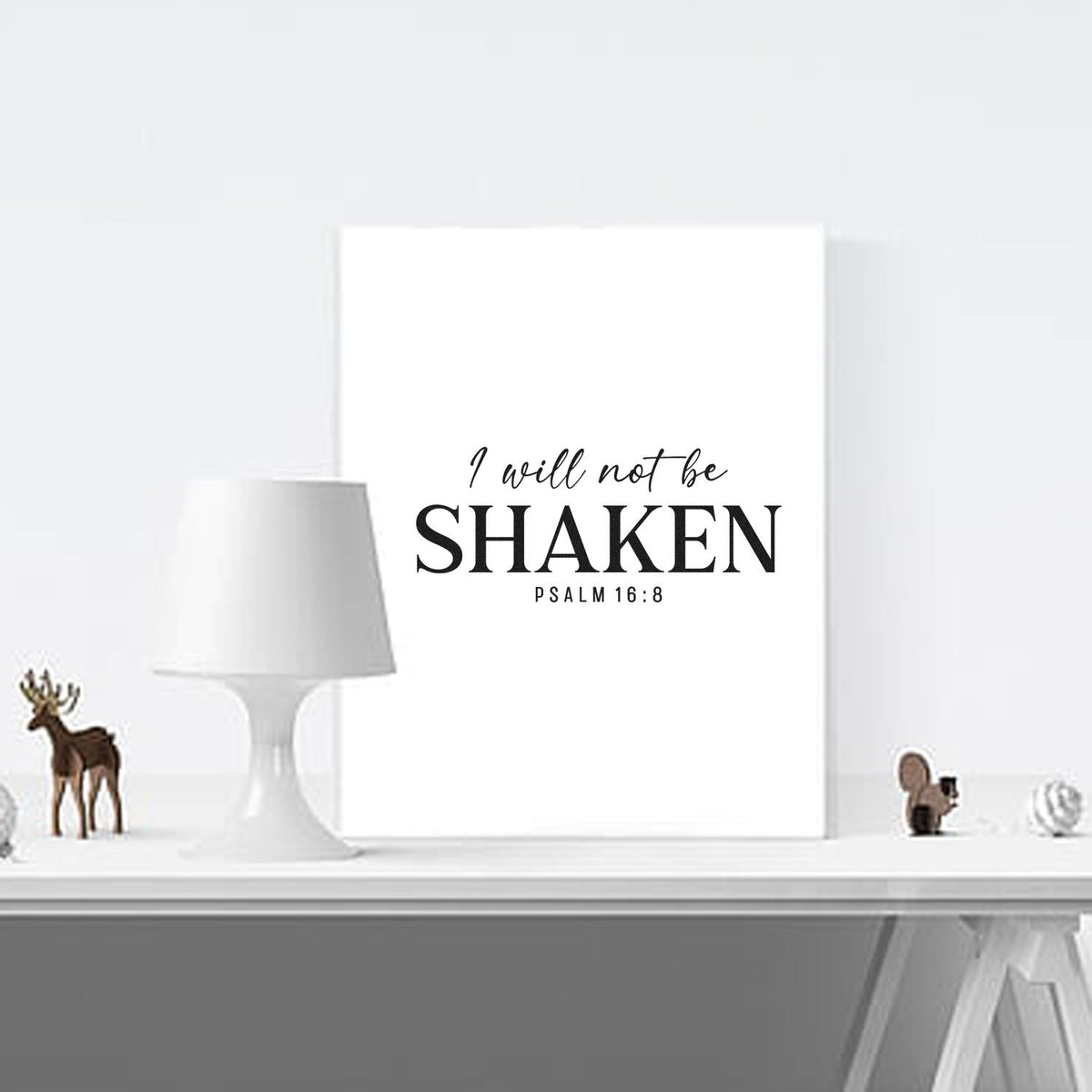 White stamp and seal decor featuring black I will not be shaken Psalm 16:8 text on a clean minimalist shelf.
