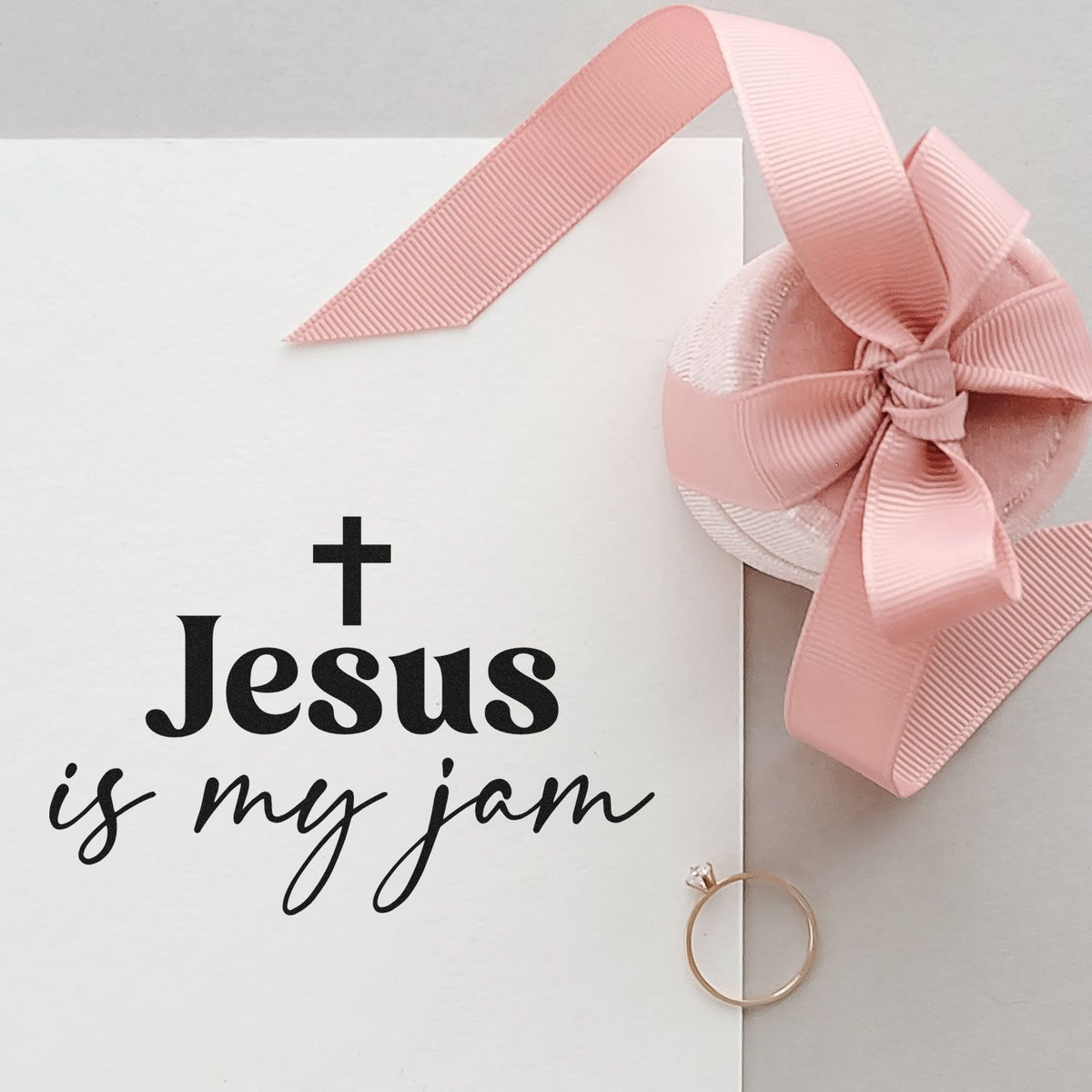 White stamp and seal card with black Jesus is my jam text, pink ribbon bow seal, and gold ring.