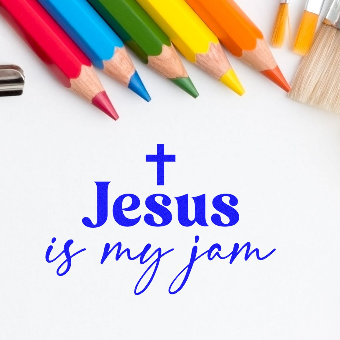 Blue Christian stamp and seal design reading Jesus is my jam with cross, surrounded by colorful pencils on white background.