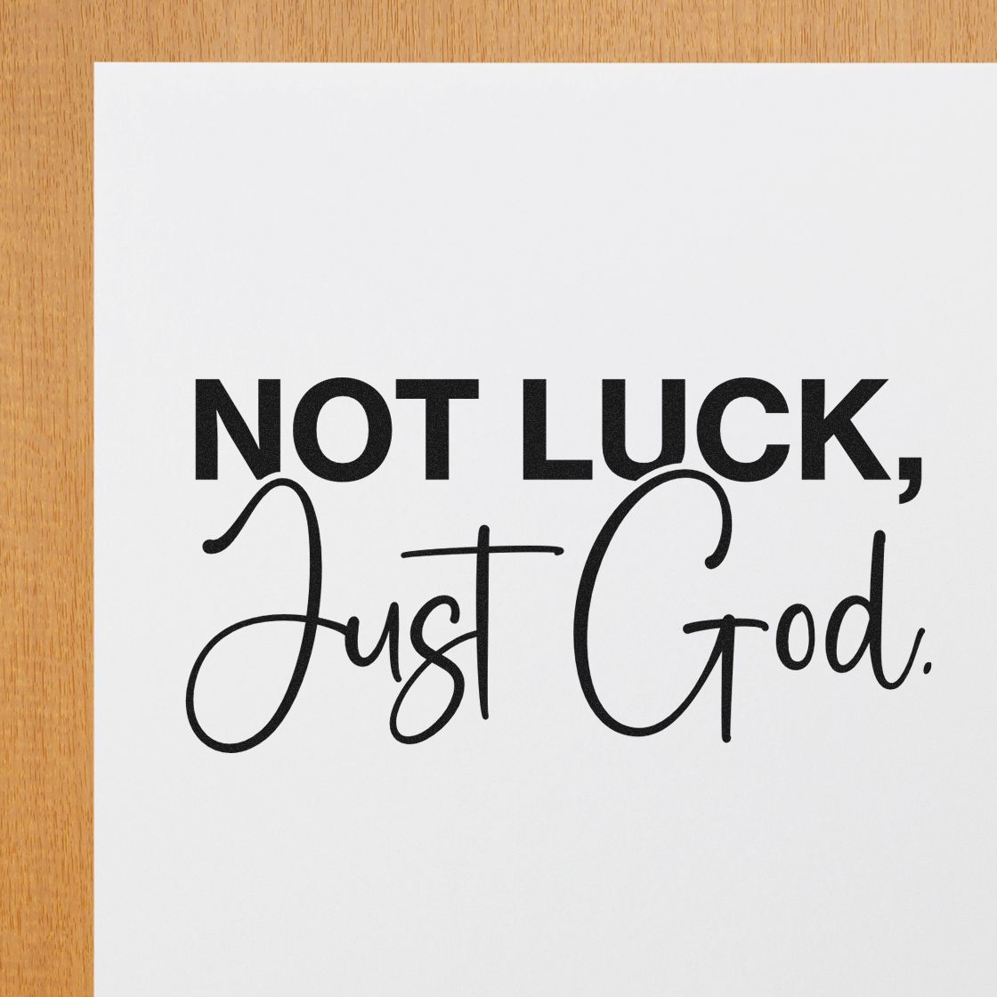 Black stamp and seal design on white card: NOT LUCK, Just God. in bold and script black text on a light wood background.