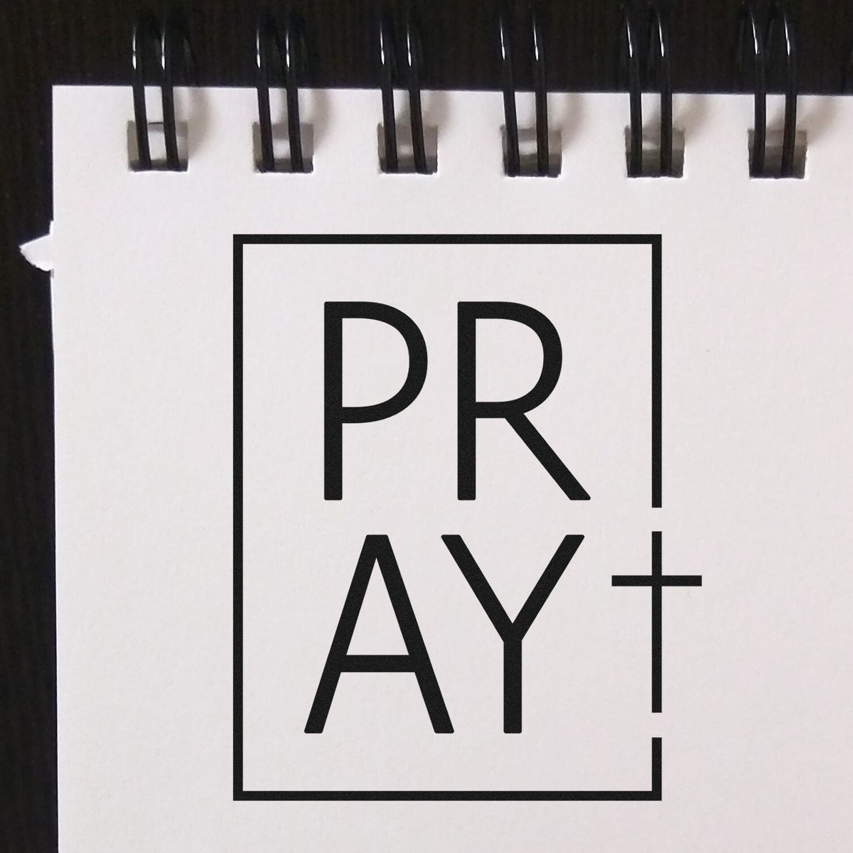 Black spiral-bound PRAY+ stamp and seal product cover with bold black logo on white background.
