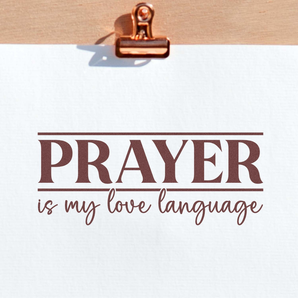 Copper clip seal stamp on white paper featuring brown PRAYER is my love language lettering